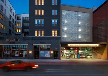 A red car is driving past a building with a sign at RoCo Apartments, Fargo, ND 58102